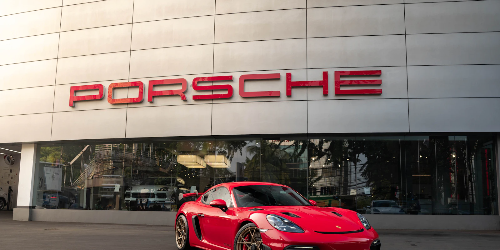 Red Porsche 718 Cayman outside a Porsche dealership